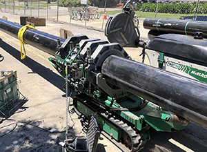 image of large black pipes and machinery to move them.
