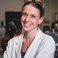 Person working in a laboratory setting, smiling confidently.